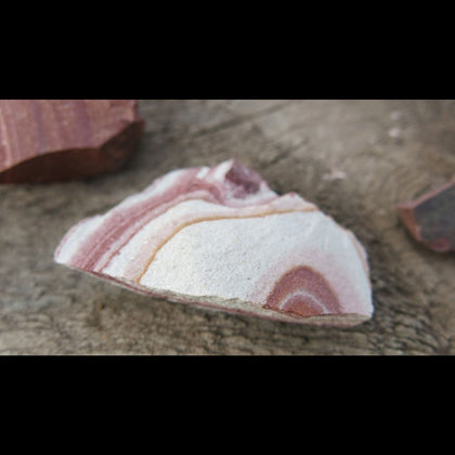 banded pink and tan wonderstone rhyolite stone on brown background