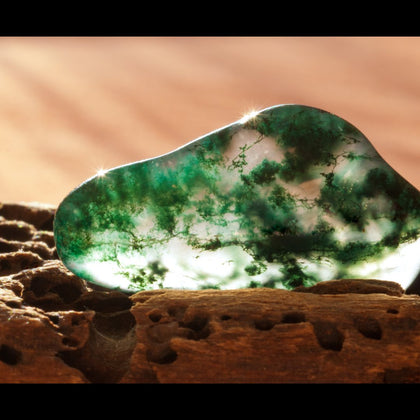 tumbled clear pebble of moss agate with green moss-like structures inside