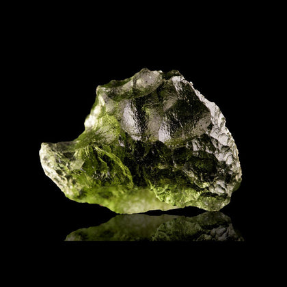piece of yellow green natural glass moldavite with dimples and fractures on black background