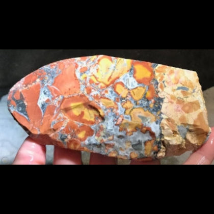 Multi colored opaque rock called maligano jasper in a hand
