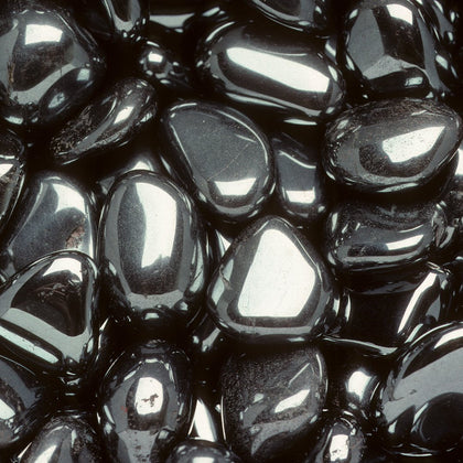 a pile of shiny dark metallic polished hematite pebbles