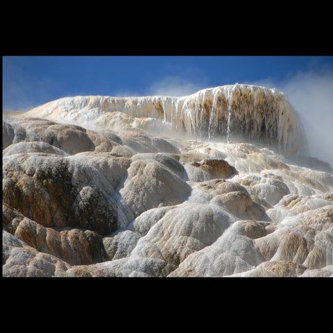 dripping Travertine mineral formations of a hot spring with a blue sky in the background