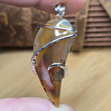 Close-up of a hand holding a unique pendant with a natural stone design.