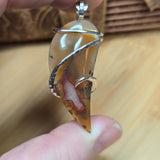 Close-up of a hand holding a Agua Nueva Agate pendant.
