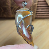 Close-up of an agate pendant with silver wire wrapping held by a hand.