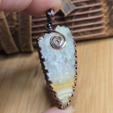 Pendant with a natural stone design held by a hand on a wooden surface