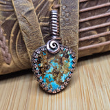 Pendant with turquoise stone and metal spiral on a textured surface