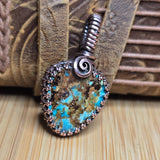 Pendant with turquoise stone and metal spiral on a wooden surface