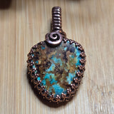 Jewelry with a turquoise stone and copper setting on a wooden surface