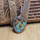 Turquoise stone pendant with copper wirework on a textured leather surface