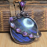 Heart-shaped pendant with purple stones and silver accents on a wooden surface