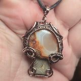 Close-up of a decorative pendant with a stone held in a hand.