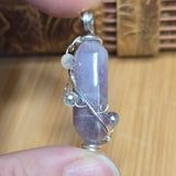 Crystal pendant held between fingers on a wooden surface