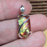 Multicolored pendant held between fingers with a blurred background