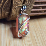 Multicolored stone pendant with silver wire wrapping on a wooden surface