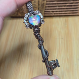 Decorative key with a colorful gemstone held by a hand on a wooden surface