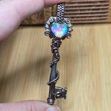 Hand holding a decorative pendant with an opal stone against a wooden background