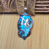 Blue and metallic marbled pendant with copper wire wrapping on a textured surface