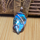 Blue pendant with copper accents on a textured surface