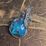 Silver pendant with a blue stone on a textured brown background