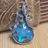 Blue pendant with silver wire wrapping on a wooden surface