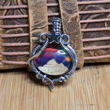 Silver pendant with a mountain and star design on a wooden surface