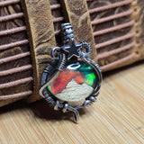 Silver pendant with a colorful design on a wooden surface