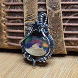 Silver pendant with a mountain design on a wooden surface