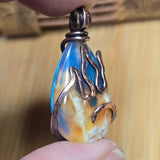 Close-up of a teardrop-shaped pendant with wavy designs on a wooden surface