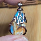 Hand holding a unique pendant with flame design against a wooden background