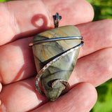 Hand holding a stone pendant with a natural background
