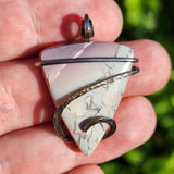 Blue and purple Jasper in sterling silver pendant held in hand on blurred green background