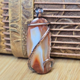 Agate pendant with wire wrapping on a textured surface
