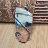 Jewelry pendant with stone and wire design on a wooden surface