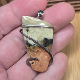 Hand holding a stone pendant with metal wire wrapping