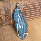 Blue feather-shaped pendant on a wooden surface