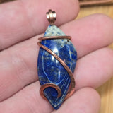 Blue stone pendant with copper wire wrapping held between fingers