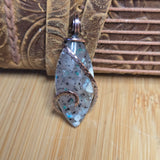 Jewelry pendant with speckled design on a textured surface