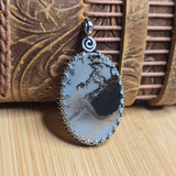 Silver pendant with a natural stone design on a wooden surface
