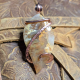 Jewelry pendant with copper wire wrapping on a textured surface