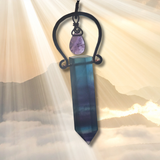 Crystal pendant with a purple stone on a soft, blurred background