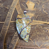 Decorative stone pendant with floral pattern on a textured surface