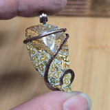 Hand holding a unique pendant with a textured surface against a wooden background