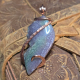 Purple, green and copper pendant on a textured surface