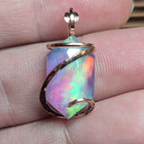 Multicolored opal pendant held between fingers