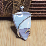 Silver-wrapped pendant with a natural stone on a woven surface