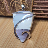 Silver and white pendant on a wooden surface with a brown textured background
