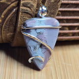 Purple stone pendant with sterling wire wrapping on a textured surface
