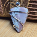 Pink stone pendant with silver wire wrapping on a wooden surface