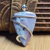 Purple stone pendant with silver accents on a textured brown surface